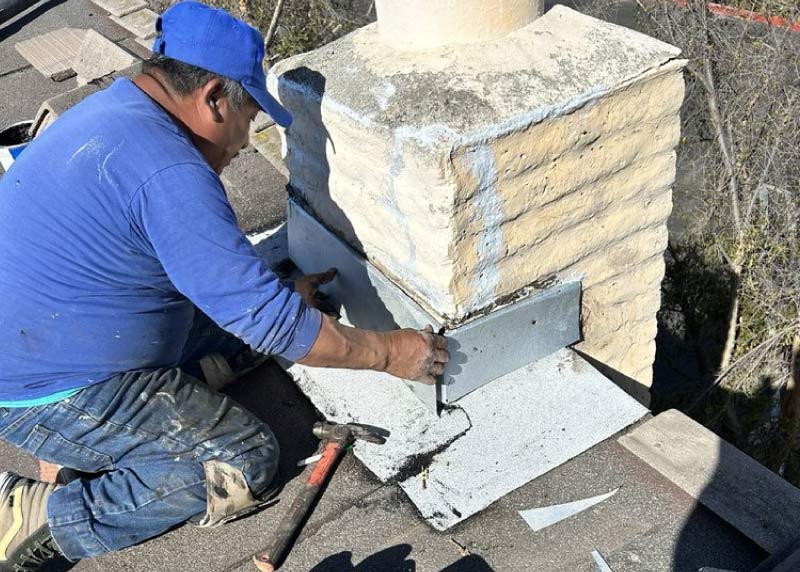 Roofer repairing flashing around a chimney during a roof repair in Orange County