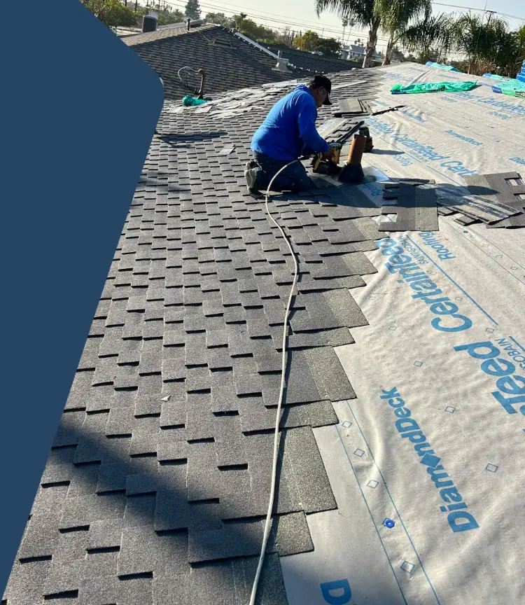 Roofer nailing down asphalt shingles over CertainTeed underlayment on a residential roof