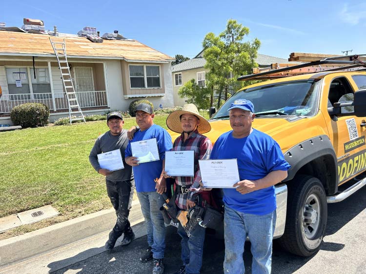 roofers-with-certifications OC Roof Contractors crew holding training certifications in front of the company truck