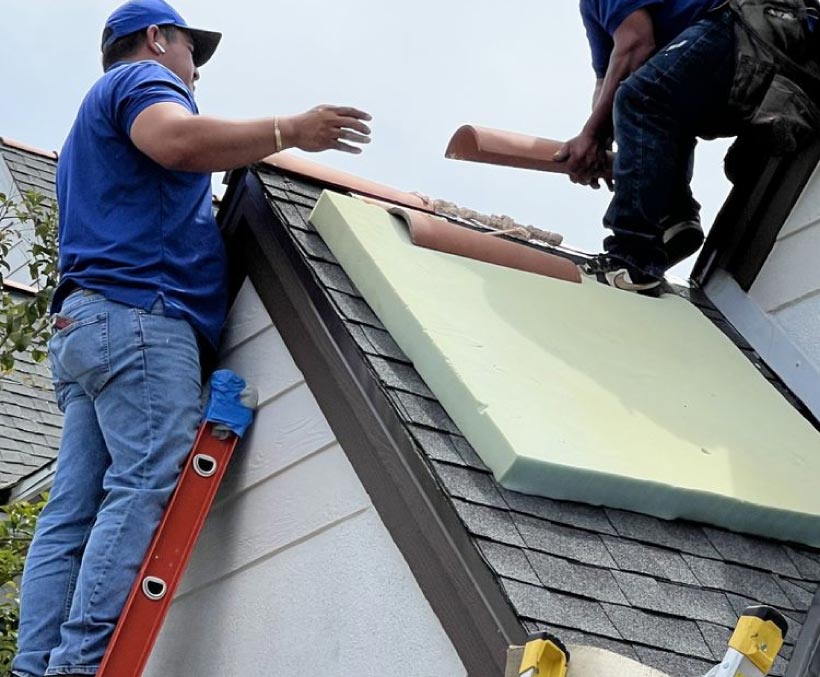 roofing-work-in-progress Roofers installing clay tile roofing on a home's dormer section